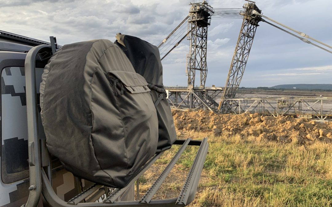 VW universal carrier, bike carrier with Delta-BAGS Wheel-Cover and Ortlieb bag. In the background lignite excavator in the open pit mine Inden