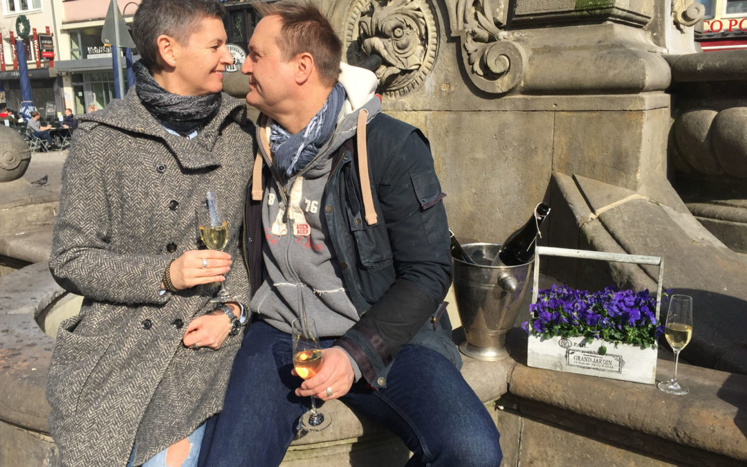 Retour en arrière : Torgit et Marc le jour de leur mariage, assis près de la fontaine, sur l'Alter Markt, à Cologne