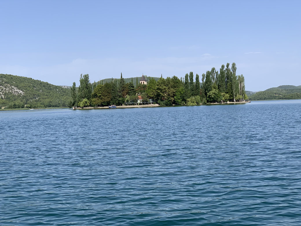Blick übers Wasser auf die Insel Visovac und das Franziskanerkloster bei strahlendem Sonnenschein