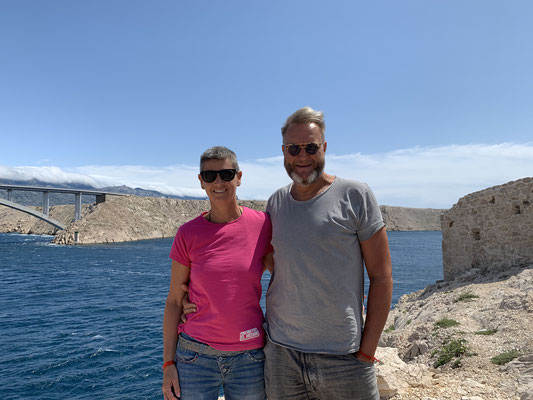 Torgit y Marc sonríen felices frente al puente Paški most que lleva a Pag