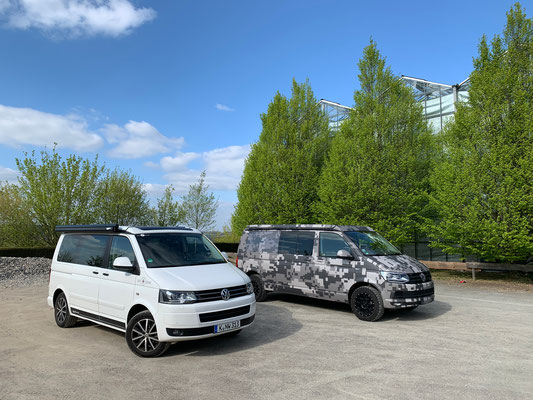 White T5 California next to T6 Spacecamper in camouflage pixel camouflage wrap