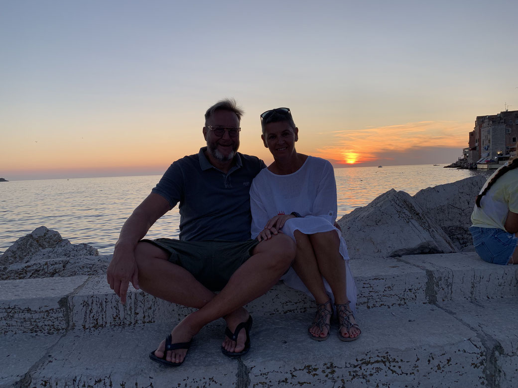 Torgit e Marc siedono sul muro del molo di Rovigno prima del tramonto