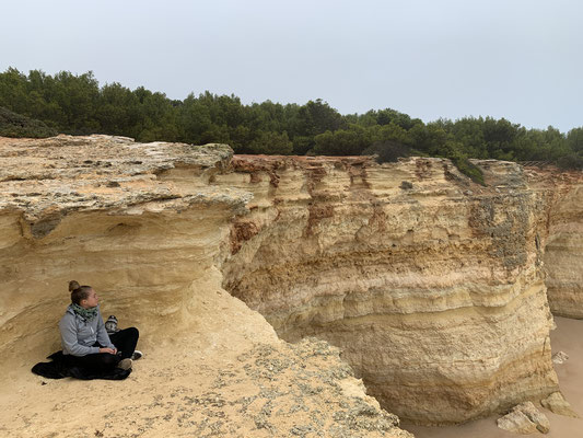 Meisje in een yogastoel bij de grot van Benagil in de Algarve, boven het zandstrand met dezelfde naam, Praia de Benagil.