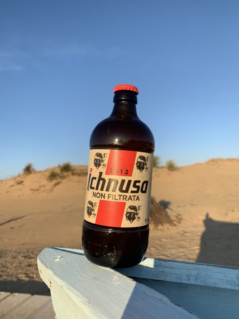 Botella de cerveza sarda en la playa de Piscinas 
