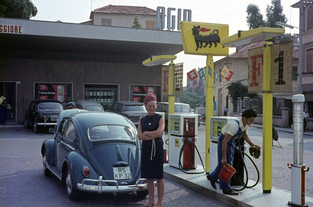 Italienurlaub: Karin Häusgen vor altem VW Käfer vor Agip Tankstelle