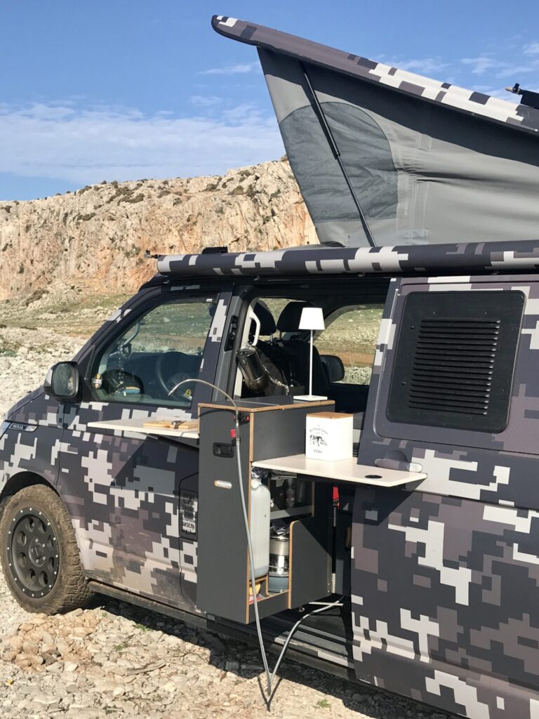 Porte coulissante du SpaceCamper de planBwagen avec cuisine pivotant vers l'extérieur