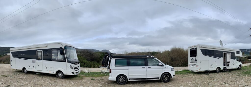 small white VW California parked between 2 large Concord