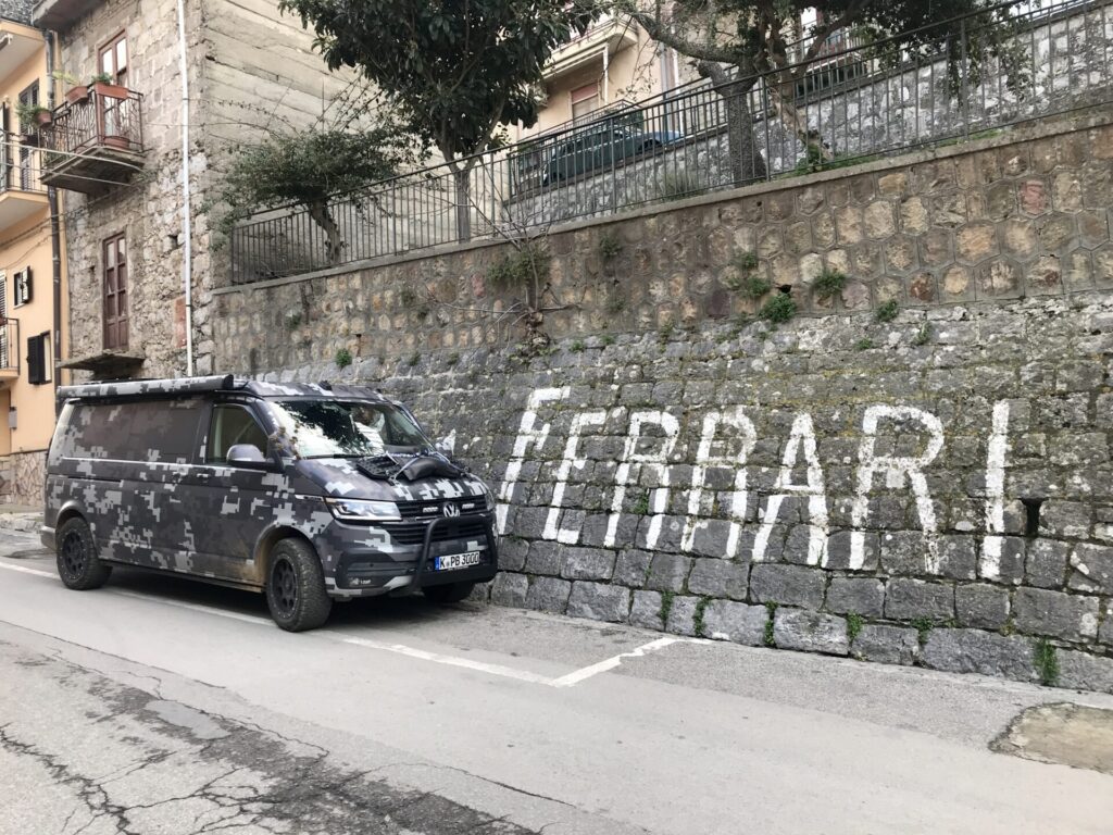 planBwagen vor dem Schriftzug 'Ferrari' auf einer Mauer in Collesano