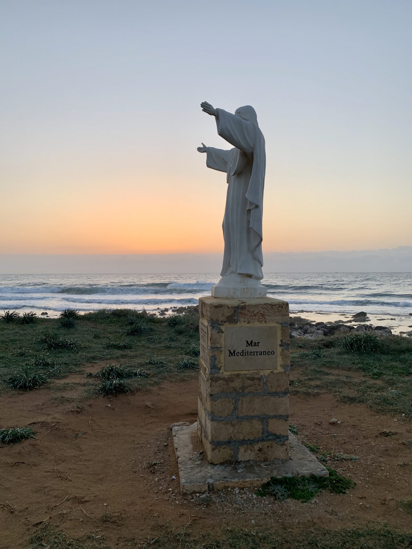 Christo statue in front of Isola delle Correnti in sunrise