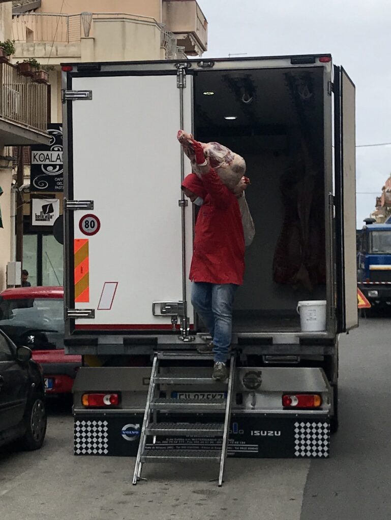 Een man laadt een stuk rundvlees uit een vrachtwagen