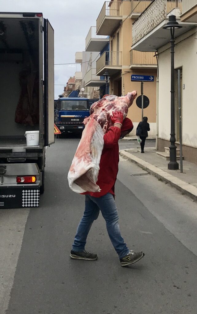 Un uomo trasporta metà di una mucca attraverso la strada