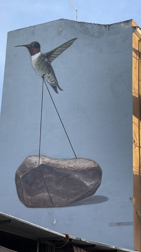 Street Art Palermo, am Ballaro, „Fides“ Andrea Buglisi, ein Koibri, welcher einen Stein hochhebt 